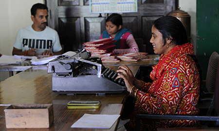 Image of a woman typing in an office in India. Photo by HPP India. 